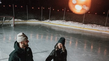 Two people holding hands on an ice rink at night.