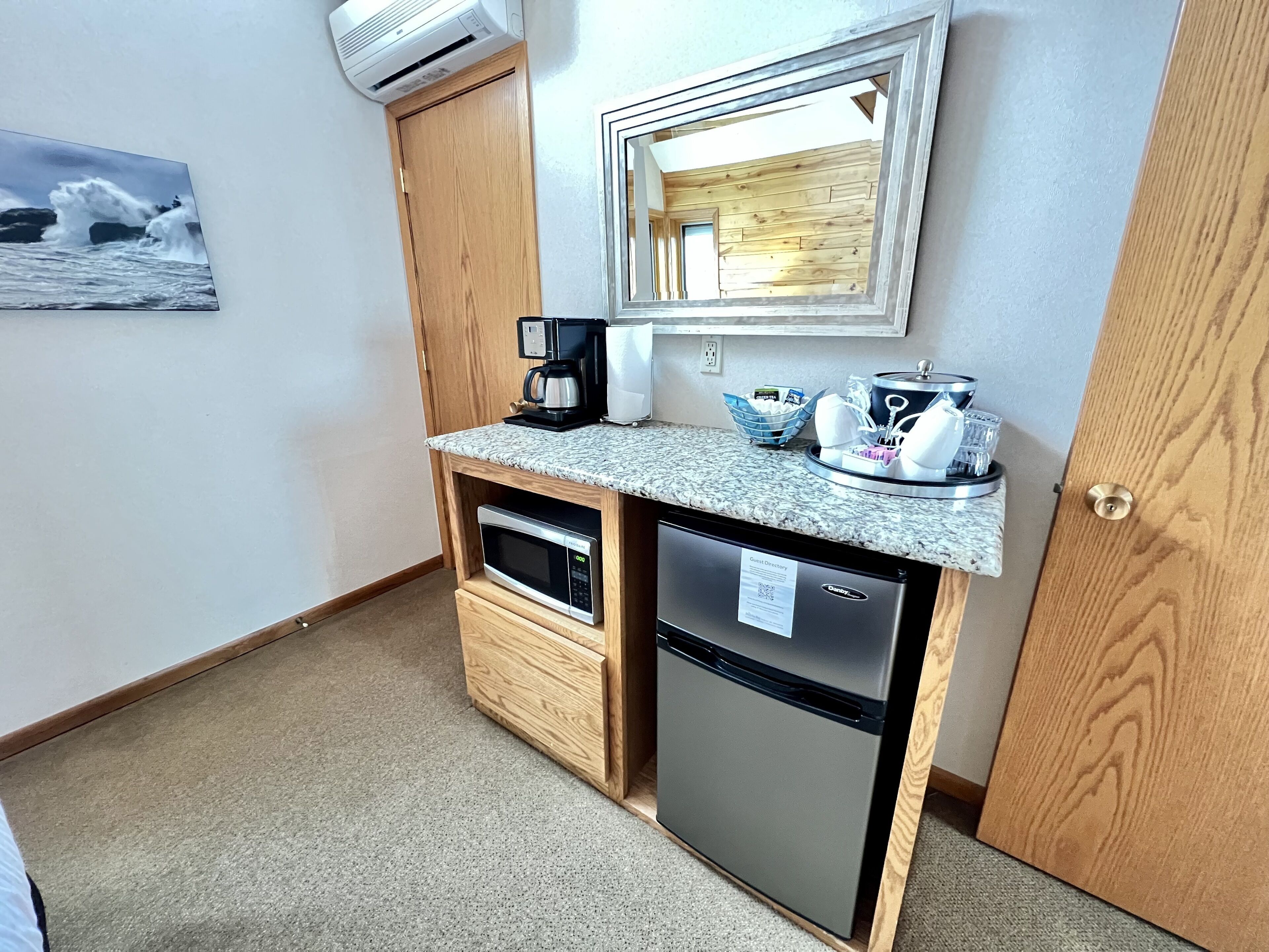 Una kitchenette compacta con microondas, cafetera y un refrigerador pequeño.