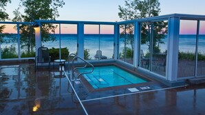 Una piscina interior con paredes de cristal, una escalera de piscina y vistas al mar.