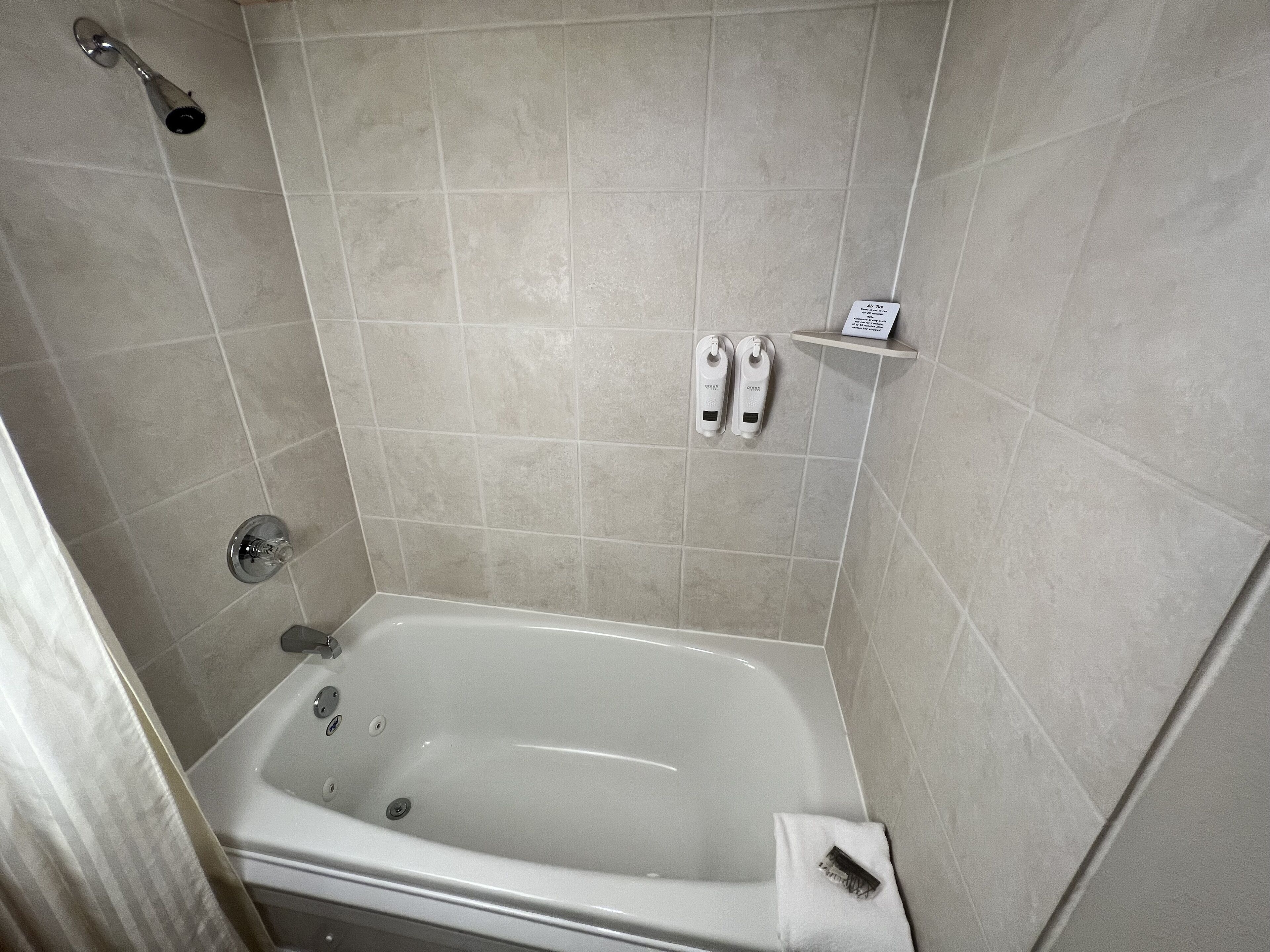 A modern bathroom with a bathtub, a showerhead, and a shelf with toiletries.