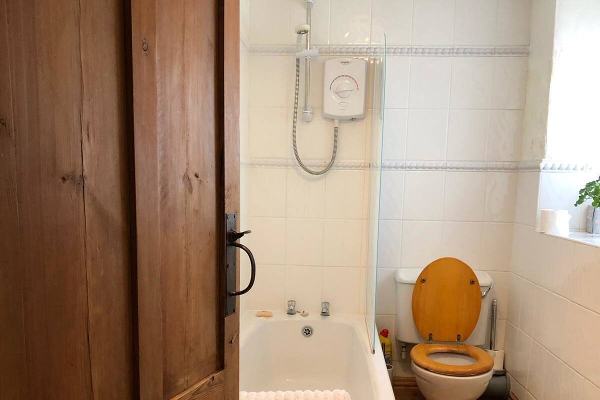 A bathroom with a wooden door, a bathtub, a toilet, and a shower.