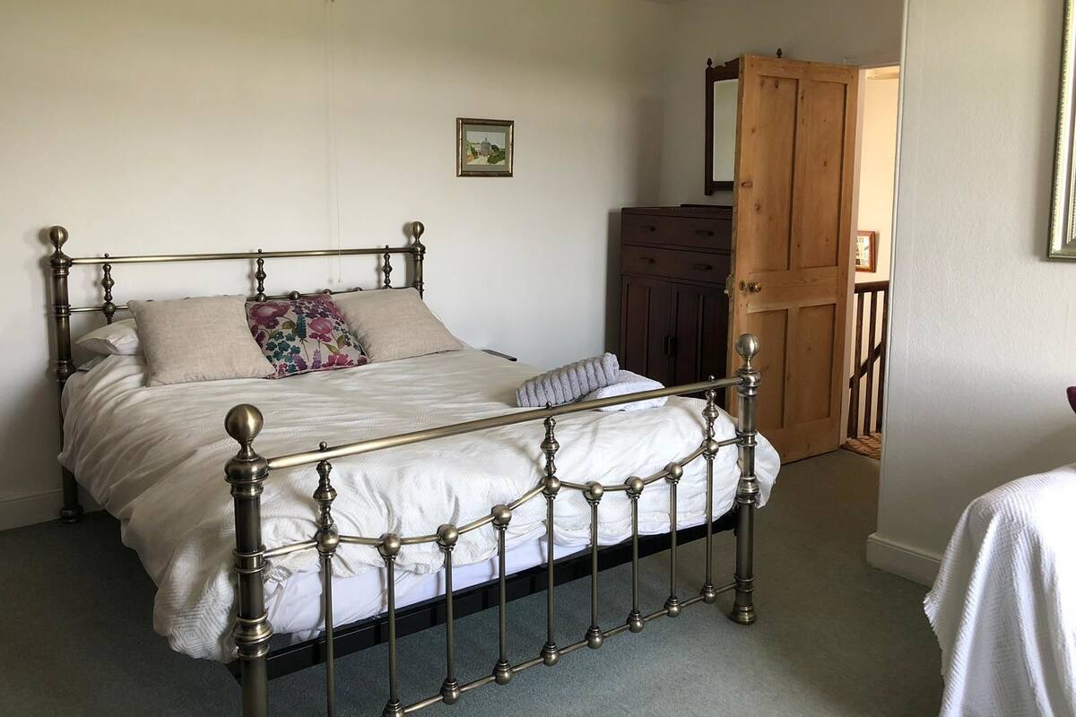 A bedroom with a four-poster bed, a dresser, and a mirror on the wall.