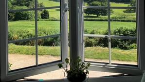 A room with large windows offering a view of a green landscape. - Tregarland Farm (Looe)