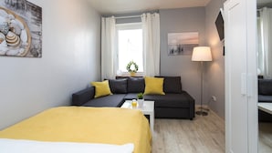 A compact room with a bed, a sofa, a small table, and a lamp. - Ferienwohnung Raab (Nuremberg)