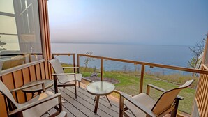 A deck with outdoor furniture, a glass table, and a view of the water. - Surfside on Lake Superior (Tofte)