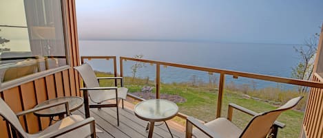 En terrasse med udendørs møbler, et glasbord og udsigt til vandet.