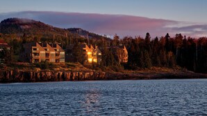 A waterfront property with modern buildings, a dock, and a forested hill in the background. - Surfside on Lake Superior (Tofte)