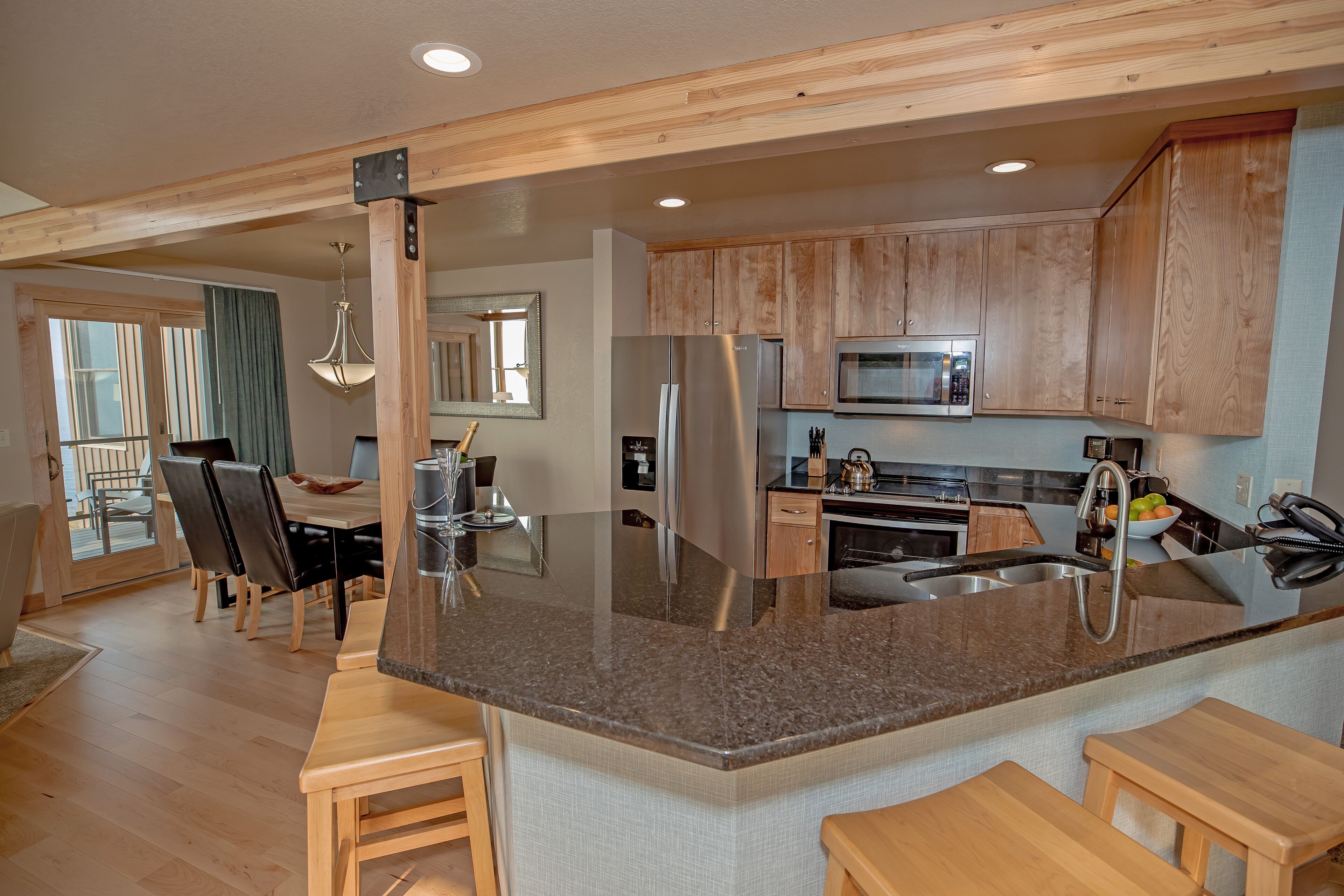 A modern kitchen with wooden cabinets, granite countertops, and stainless steel appliances.