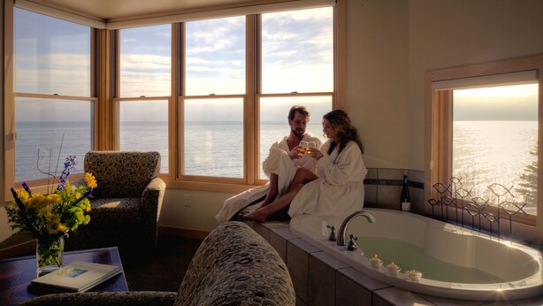 A room with a large window, a bathtub, and a chair. - Surfside on Lake Superior (Tofte)