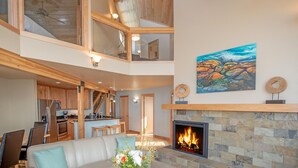 A spacious living area with a fireplace, a dining area, and a kitchen. - Surfside on Lake Superior (Tofte)