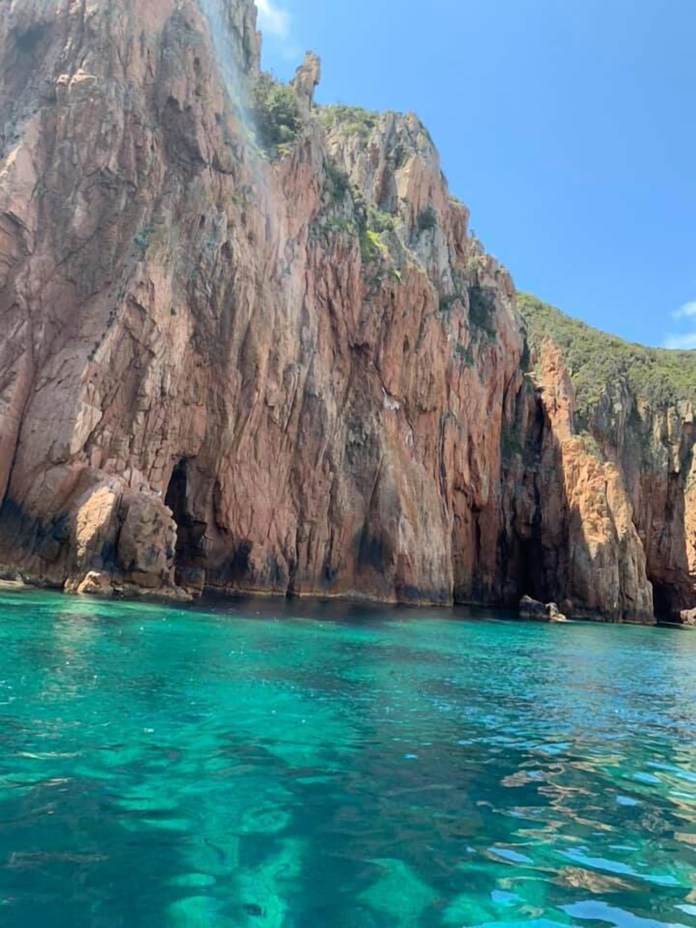 A coastal cliff with clear turquoise water.