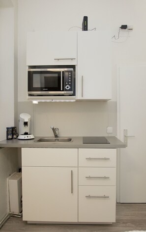 Prepare meals and brew coffee in this compact kitchenette, equipped with a microwave oven, coffee maker, and sink.