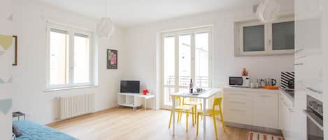 Amplia sala de estar y comedor con cocina, televisor y una mesa de comedor con sillas.