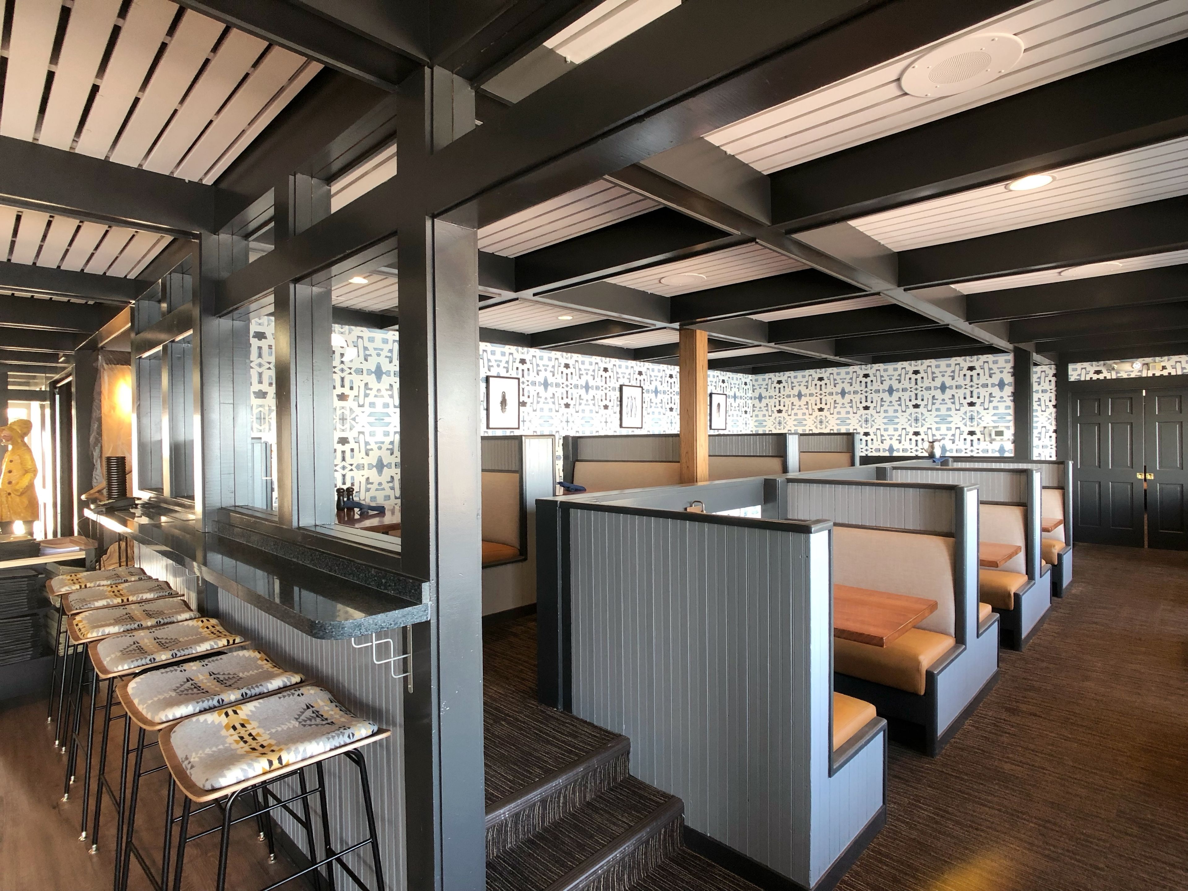 Un interior moderno con techos altos, asientos de bar y estaciones de trabajo separadas.