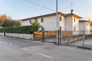 A residential building with a gated entrance, a paved driveway, and a clear sky.