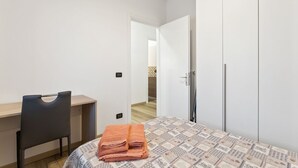 A bedroom with a bed, a desk, and a chair. There is a door leading to another room. - Cassola - Via Loria 12 (Cassola)