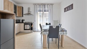 A modern kitchen with a dining area, featuring a table with chairs, a refrigerator, and a microwave. - Cassola - Via Loria 12 (Cassola)