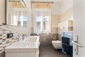 A bathroom with a white sink, a toilet, and a shower area.