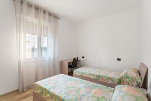 A bedroom with two single beds, a desk, and a chair.