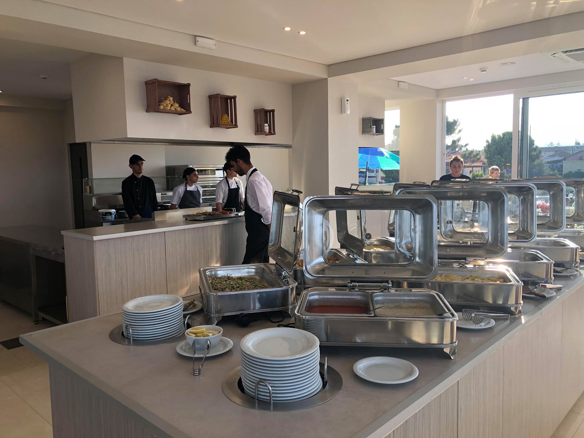 Un área de bufé con varias estaciones de comida, una barra de atención y vistas al exterior.