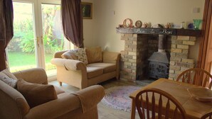 Ein gemütliches Wohnzimmer mit einer Couch, Sesseln, einem Esstisch und einem Kamin.