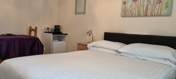 A bedroom with a bed, a desk with a chair, a nightstand, and a wall-mounted mirror. - A Home From Home 2 (Plymouth)
