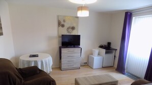 A living room with a sofa, a small table, a TV, and a cabinet. - A Home From Home 2 (Plymouth)