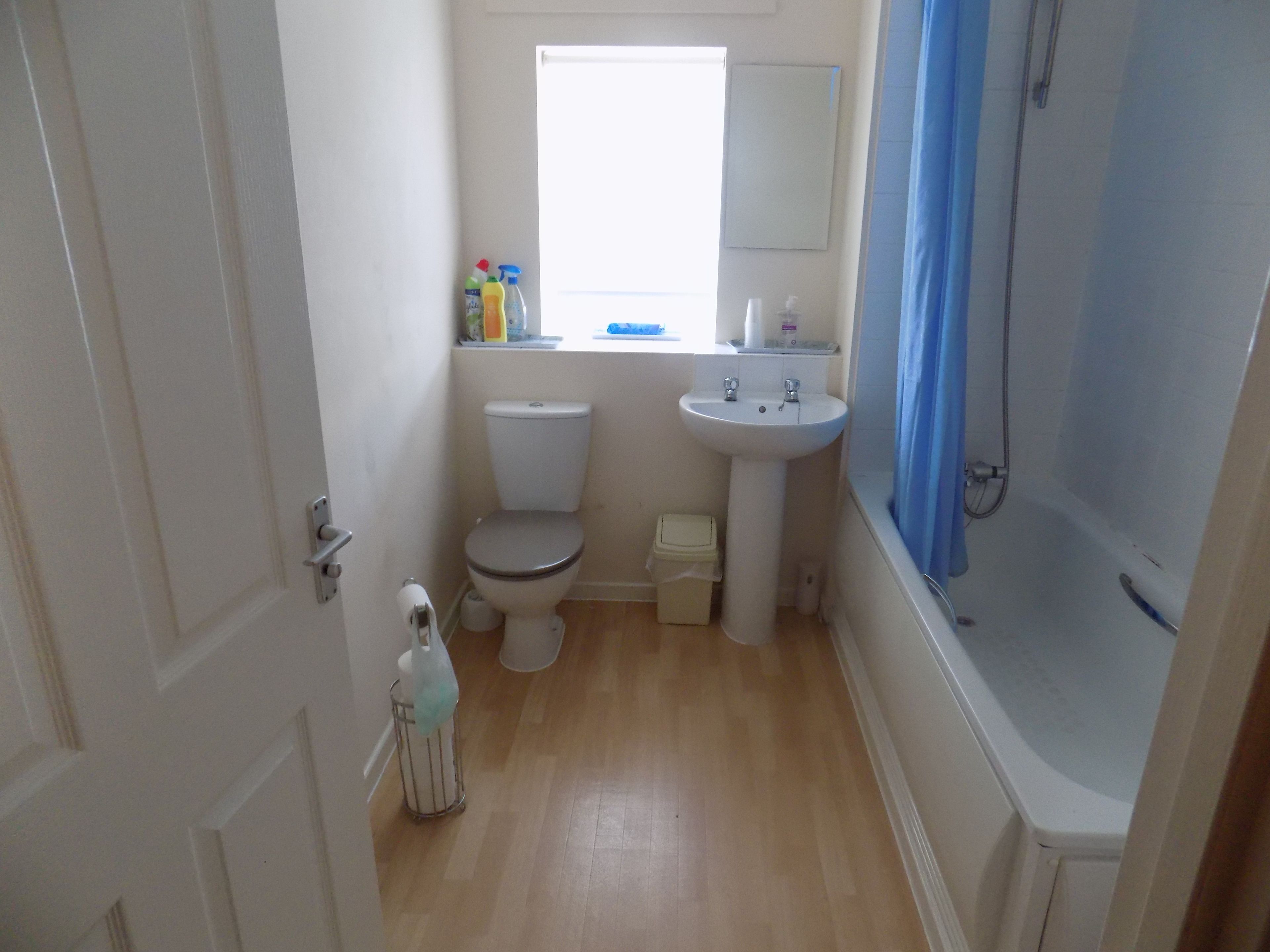 A small bathroom with a toilet, sink, and shower.