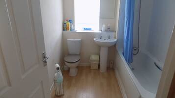 A small bathroom with a toilet, sink, and shower.