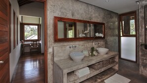 Une salle de bain dotée d’un grand miroir, de deux lavabos et d’un meuble-lavabo avec des paniers.