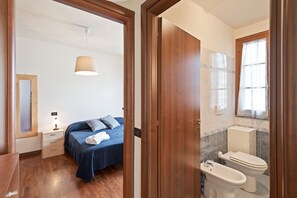 Une chambre à coucher comprenant un lit, une table de chevet, une lampe, ainsi qu’une salle de bain avec des toilettes et un lavabo.