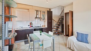 A compact kitchen with a dining area, a staircase, and a sofa with a patterned pillow. - Lucca - Via Viaccia 155 (Lucca)