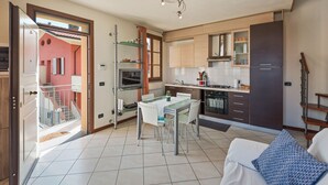A modern kitchen with a dining area, a staircase, and a view of a red building outside. - Lucca - Via Viaccia 155 (Lucca)