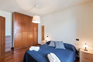 Une chambre avec un grand lit, une armoire en bois, des tables de chevet et un luminaire suspendu.