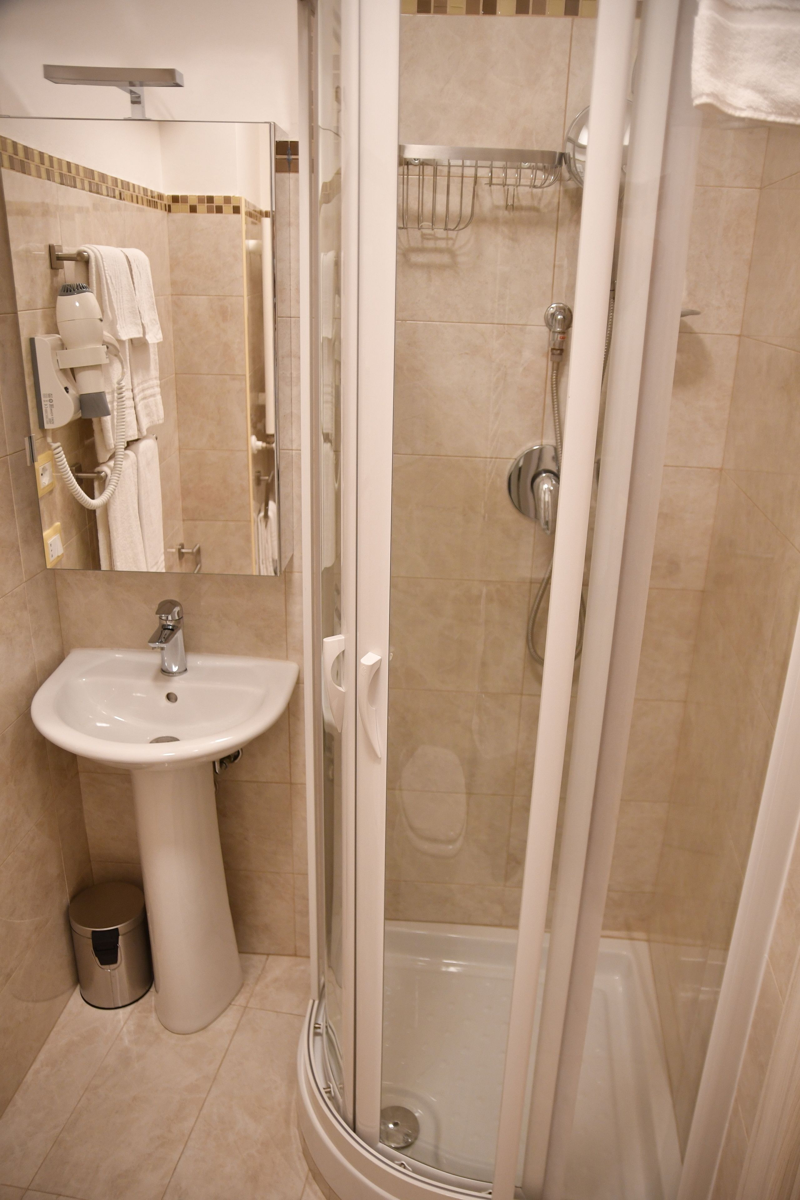 Un baño moderno con lavamanos, espejo y ducha.