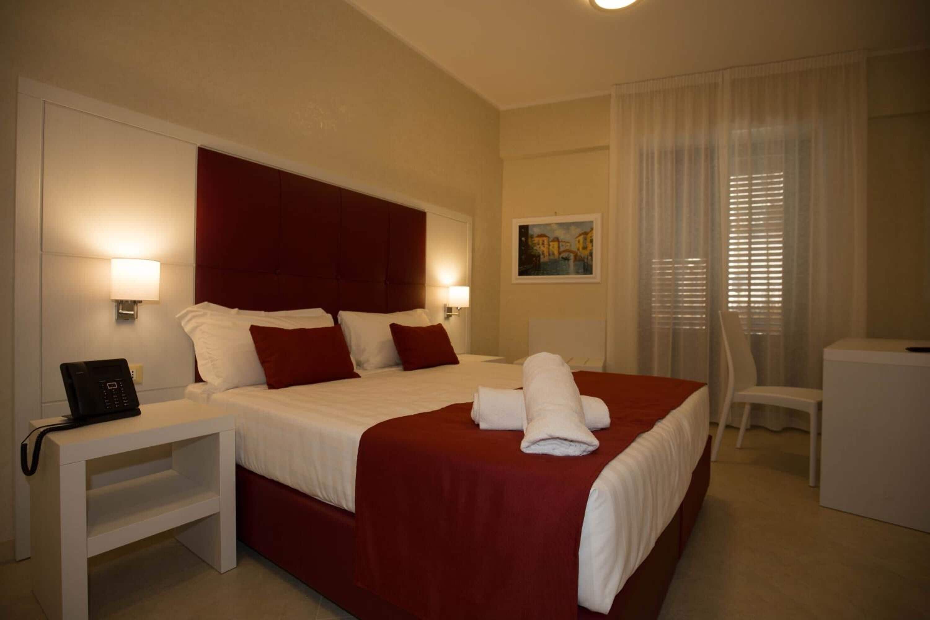 A hotel room with a large bed, two bedside tables, a desk, and a chair.
