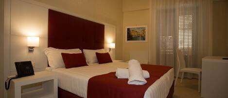 A hotel room with a large bed, two bedside tables, a desk, and a chair.