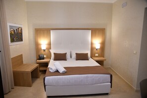 A hotel room with a large bed, two bedside tables, a wooden bench, and a painting on the wall. - La Serenissima Hotel (Palermo)