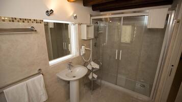 A bathroom with a glass-enclosed shower, a pedestal sink, and a towel rack.