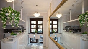A modern kitchen with white cabinetry, a large mirror, and two bar stools. - La Serenissima Hotel (Palermo)