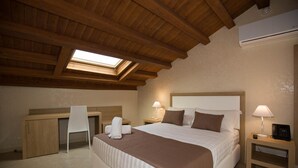 A hotel room with a large bed, a desk, a chair, and a skylight. - La Serenissima Hotel (Palermo)