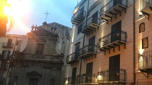 A street view of a building with multiple balconies, a vintage facade, and a clear sky. - La Serenissima Hotel (Palermo)