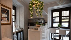 A modern kitchen with a central island, a coffee machine, and a window with a view of the street. - La Serenissima Hotel (Palermo)