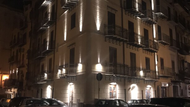 A multi-story building with illuminated balconies and a parking area in front. - La Serenissima Hotel (Palermo)