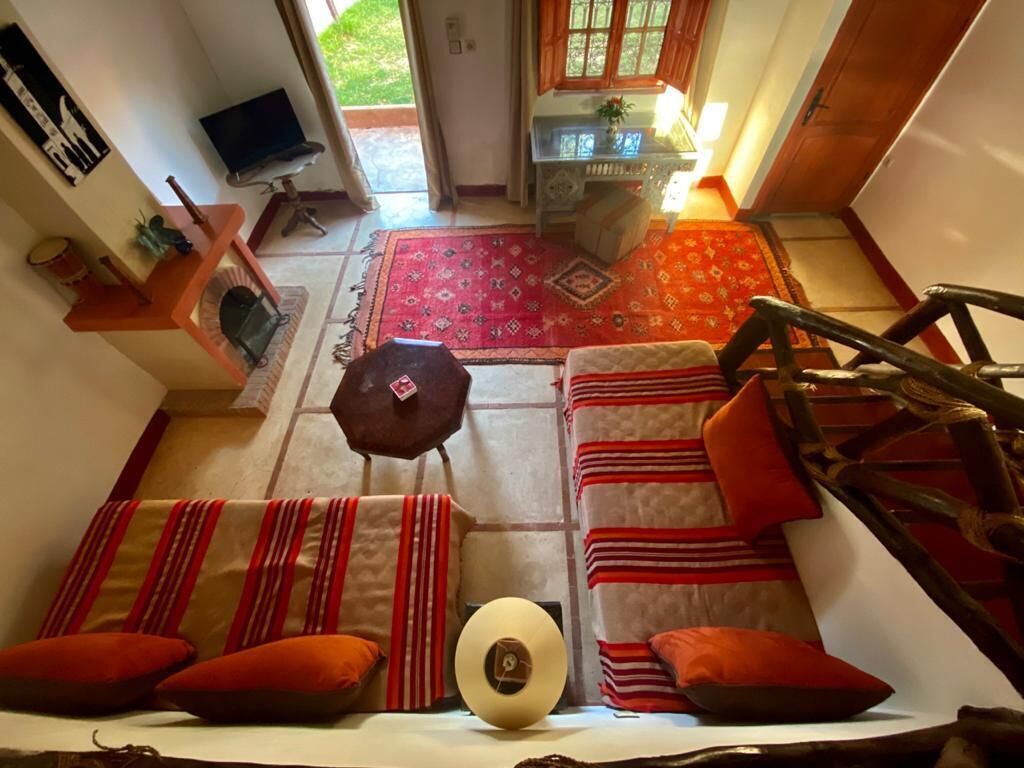 Una sala de estar acogedora con un sofá, una mesa de centro y un televisor. Se ve un ventanal con vistas al exterior.