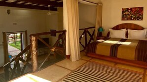 A bedroom with a bed, a nightstand, a painting, and a staircase leading to an outdoor area. - Relais Esmeralda (Lalla Takarkoust)