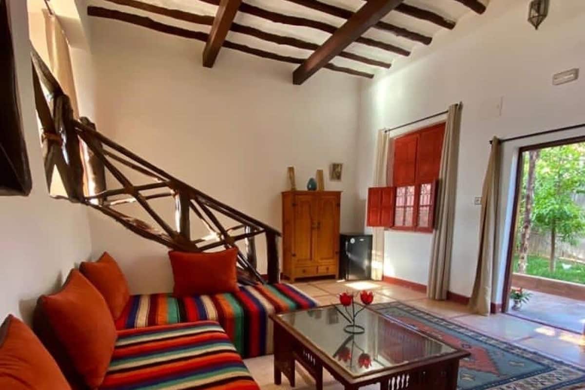 A living room with a striped sofa, a wooden coffee table, and a staircase.