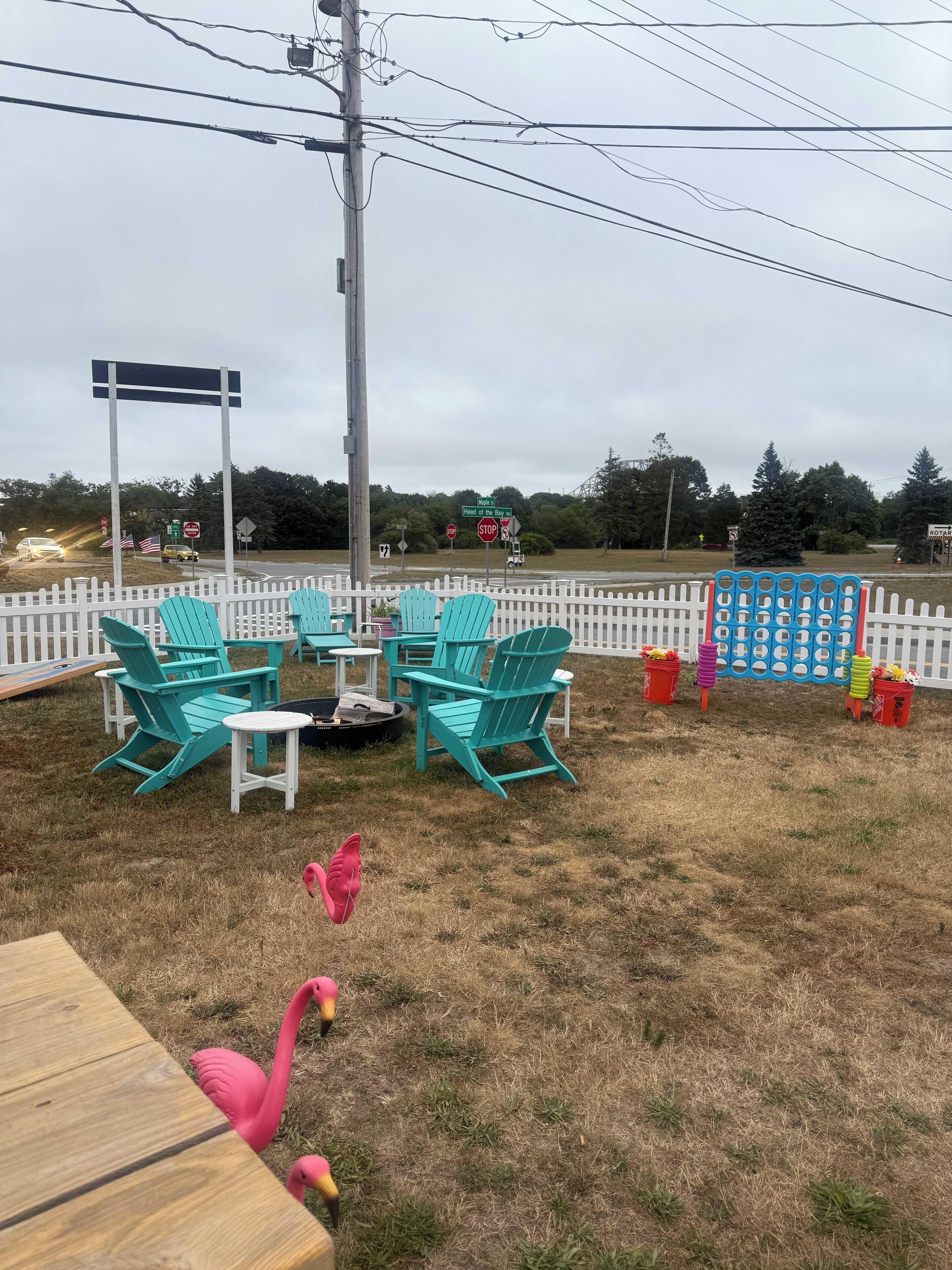 An outdoor seating area with chairs and a table, surrounded by a white picket fence.