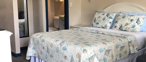 Un dormitorio con una cama, un espejo, un lavabo y un cuadro en la pared.