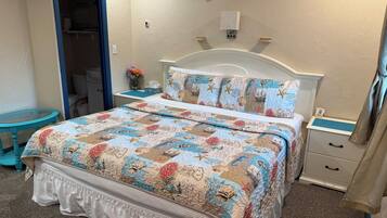 A bedroom with a bed, a nightstand, a dresser, and a bathroom visible through an open door.